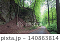 Walking through a forest trail in Hruba Skala, Bohemian Paradise (Cesky raj), Czech Republic. Towering sandstone rock formations line the path in one of the country's most popular hiking destinations. 140863814
