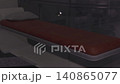 Empty emergency stretcher in ambulance bay, red vinyl mattress secured by rails, dim overhead lighting casts deep shadows, blurred medical equipment 140865077