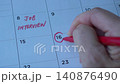 Writing down second interview appointment on table calendar with red marker. Close up view. Employment or careers concept. 140876490