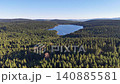 Aerial highland lake panorama framed by conifer forest and rolling hills, clear blue water, distant ridge 140885581