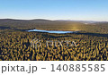 Golden hour lake glow over pine forest, warm sunlight and long shadows on shimmering blue water, atmospheric 140885585
