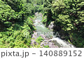 A clear stream and rocky outcrops flowing through a valley lush with new greenery. Aerial footage captured by a drone. 140889152