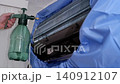 Professional worker cleaning and servicing an indoor air conditioner unit with a special tool 140912107