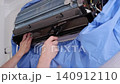 Professional handyman cleaning the dirty fan turbine of a split air conditioner with a brush 140912110