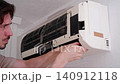 Male technician cleaning and fixing a wall-mounted air conditioning unit in a residential home 140912118