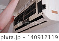 Male hands performing maintenance and closing the lid of a household air conditioner unit 140912119