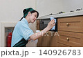 A house cleaning staff member wipes down the front of the kitchen grill. 140926783