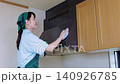 Female house cleaning staff cleaning a range hood 140926785