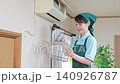 A female staff member cleaning the air conditioner filter with a vacuum cleaner. 140926787