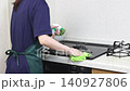 A house cleaning staff member wipes down the top of the gas stove. 140927806