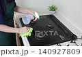 A house cleaning staff member sprays detergent on the gas stove and cleans it. 140927809