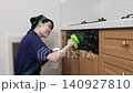 A house cleaning staff member wipes down the front of the kitchen grill. 140927810
