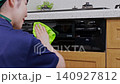 A house cleaning staff member wipes down the front of the kitchen grill. 140927812