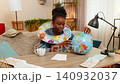 African American young woman with swim ring plans summer trip using map and airline tickets at home 140932037