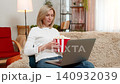 Adult woman stunned by shocking movie moment at home, holding popcorn and staring at laptop screen 140932039
