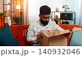 Man opening delivery box at home finding broken wireless headphones disappointed upset reaction 140932046