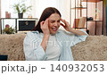 Young woman sitting on sofa holding head suffering from strong headache feeling uncomfortable pain 140932053