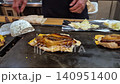 Cooking and cutting Okonoiyaki on teppan iron plate Osaka Japan traditional food 140951400