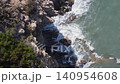 The camera shows waves hitting rocks along a shoreline. The water moves swiftly as it splashes against the coast. The view captures the natural beauty of this seaside location. 140954608