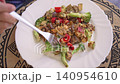 People gather around a table to share a meal made of fresh vegetables and grilled meat. They discuss, laugh, and enjoy their time together at lunchtime. 140954610