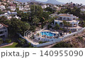 The video shows several coastal homes in Almunecar, Spain. These homes have pools and are by the sea. People are enjoying the sunny weather. The view highlights nature and architecture. 140955090