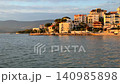 Scenic coastal view of Gulluk, Turkey, featuring white resort hotels and residential buildings along the waterfront, illuminated by the warm glow of late afternoon sun. High quality 4k footage 140985898