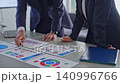 一群商務人士一邊查看文件一邊交談。 （會議、管理、策略、公司、數據、行銷） 140996766