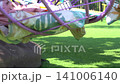 Young boy playing with colorful steering wheel equipment at a sunny outdoor public park playground 141006140