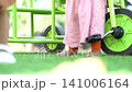 A low angle close up view of a child riding a bright green tricycle on a lush green grass lawn in a park. 141006164