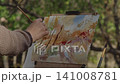 Close-up, the artist at the easel paints a forest landscape with watercolor 141008781