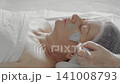 The process of applying an alginate mask to the face of an elderly woman in a beauty salon 141008793