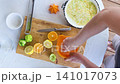 person squeezing citrus fruits on wooden cutting board in kitchen counter top view focused and productive food preparation scene with orange and green colors and clean background. 141017073