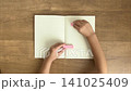A child's hand sticking a pink sticky note into a notebook (4K silent slow-motion video) 141025409