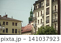 Ivano-Frankivsk, Ukraine - July 13, 2023: photo rare architectural buildings historic part city, cloudless summer day, birds flying sky, balconies green spire tower visible. People stroll calmly along 141037923