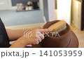 A brown hat is maintained with a wooden brush in a quiet indoor setting, highlighting dust removal and personal accessory care. 141053959