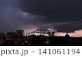 Dark ominous storm clouds rolling over a city skyline at night. Dramatic urban weather with purple twilight glow and shelf cloud formation 141061194