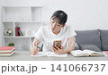 A teenage girl studying while looking at her smartphone 141066737