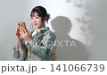 Portrait of a teenage girl wearing a yukata using a smartphone 141066739