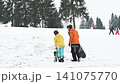 Snowboarding lesson: An instructor guides a young snowboarder on a snowy slope, surrounded by winter trees. 141075770