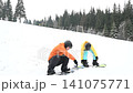Snowboarders prepping for a run on a snowy mountain slope. A winter sports scene. 141075771
