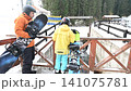 Snowboarders pause on a snowy bridge, enjoying the winter scenery. A father and child take a break from their snowy adventure. 141075781
