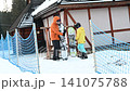 Snowboarders prepare for a day on the slopes, adjusting their equipment outside a snowy lodge. 141075788