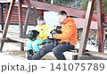 Father and son prepare for a day of skiing, adjusting their helmets on a snowy day. 141075789