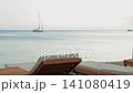 Comfortable wooden sun loungers overlooking a calm sea at sunset, with anchored sailboats on the horizon and soft pastel evening light  on the Albanian coast 141080419
