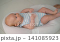 Active baby kicking legs in soft baby nest on floor. 141085923