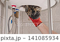 Plumber Removing Limescale And Mineral Deposits From Water Heater During Maintenance Service, Showing Hard Water Effects And Appliance Cleaning Process 141085934