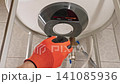 Technician Completing Water Heater Maintenance By Installing Cover Panel And Checking System Operation After Cleaning And Repair Service 141085936