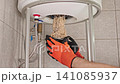 Plumber Removing Water Heater Heating Element Covered With Heavy Mineral Deposits During Maintenance, Showing Hard Water Effects, Limescale Buildup And Appliance Cleaning Process 141085937