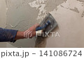 A person applies plaster to a drywall surface. The task takes place in a residential setting. Tools and plaster are used to create a smooth finish 141086724