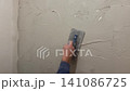 The process shows a person applying plaster onto a wall in a small room. The focus is on the steps taken to cover the wall smoothly and evenly 141086725